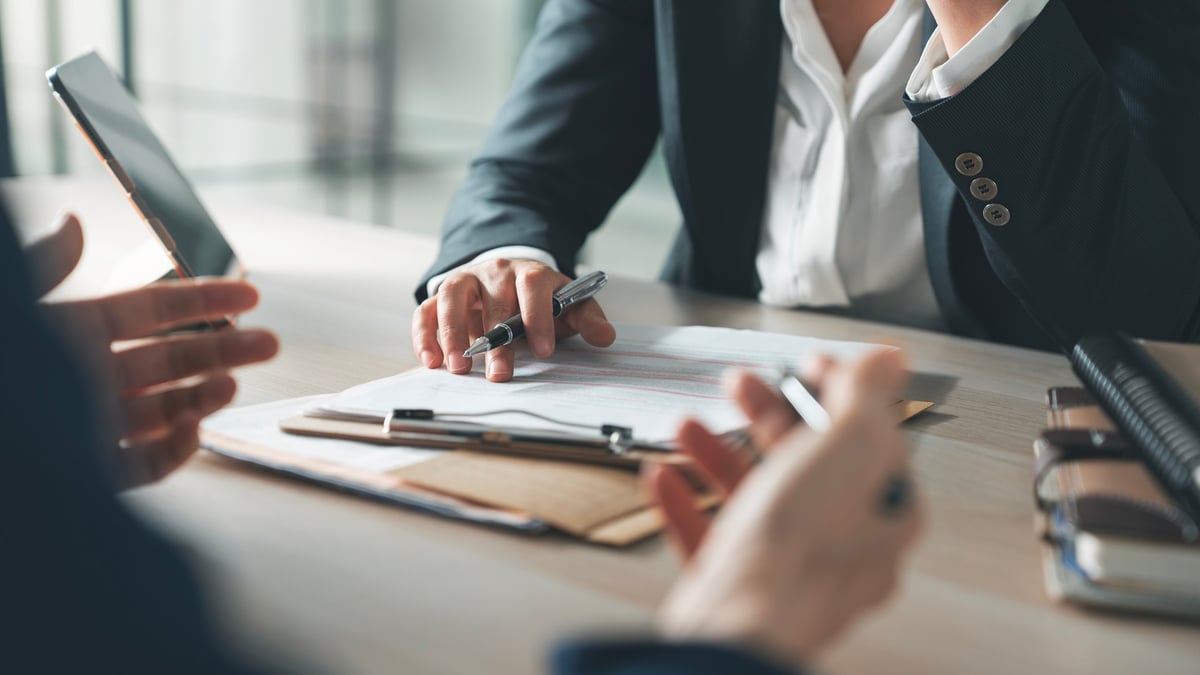 Empresario y director financiero revisando información financiera con un asesor en una oficina moderna